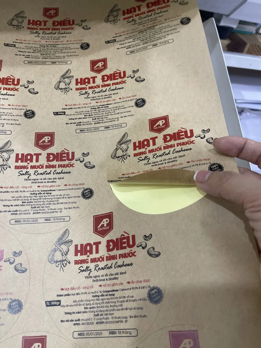 tay bóc tem nhãn khỏi tờ decal tại xưởng In Đức Lộc